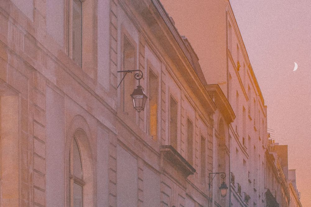 Historic European street with ornate stone buildings and lanterns at dusk creating a warm, romantic atmosphere.