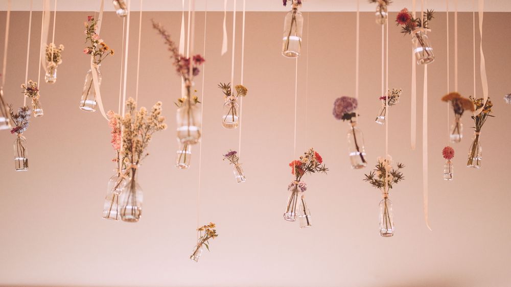 Delicate dried flowers and glass vials hang from strings creating an ethereal ceiling installation.