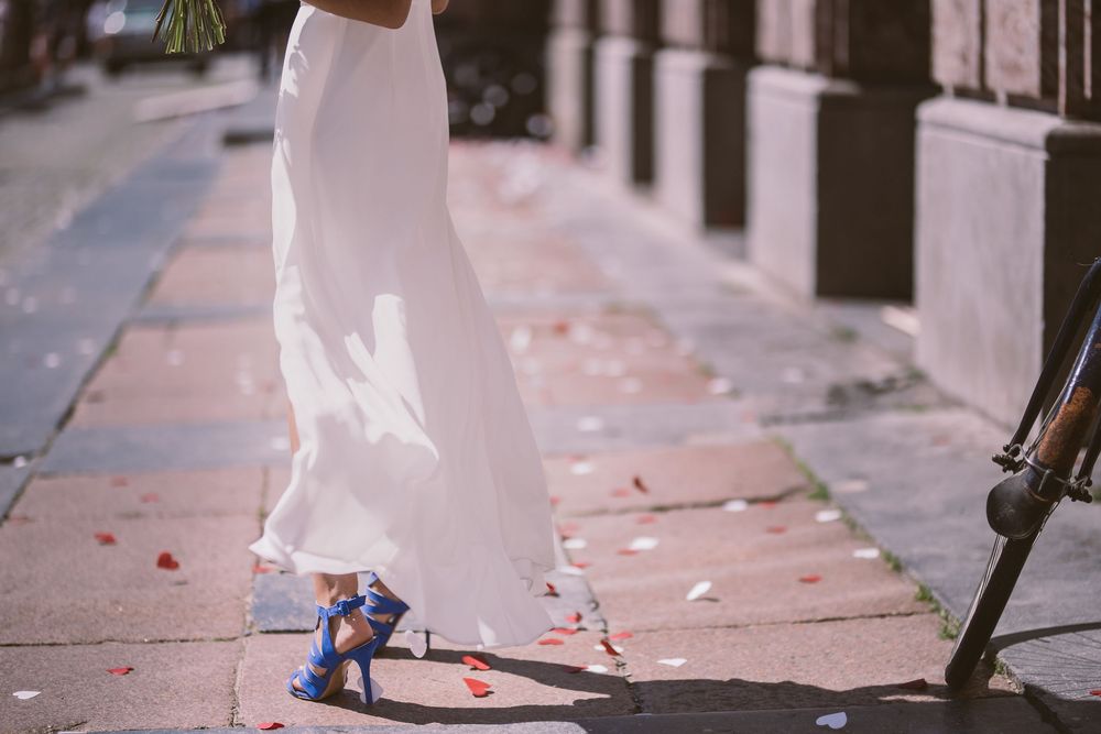 A bride's white wedding dress and blue shoes are captured in a series of walking shots on a stone pathway.