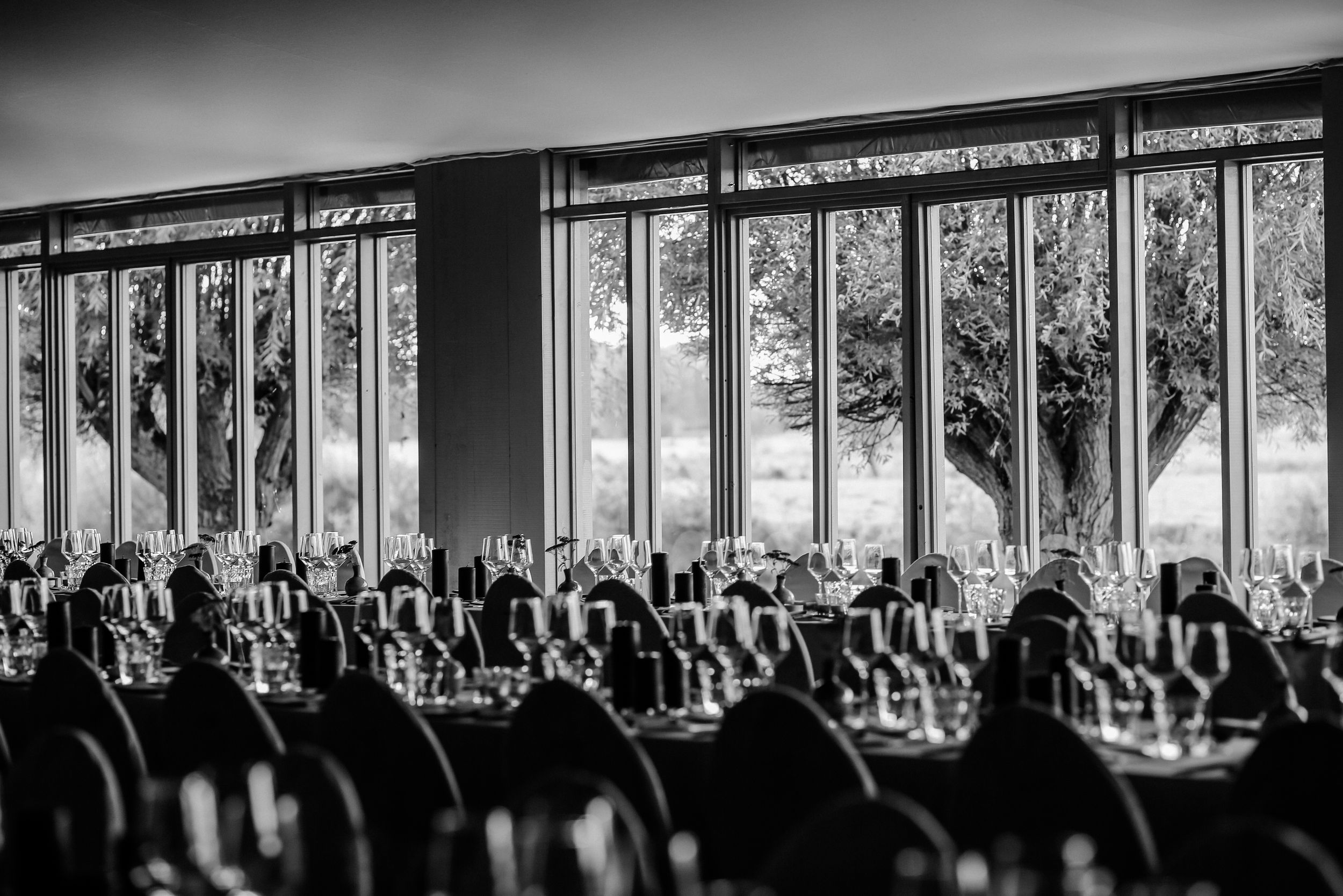 A panoramic black and white photograph showing silhouettes of people against a row of bright windows in a gallery setting.