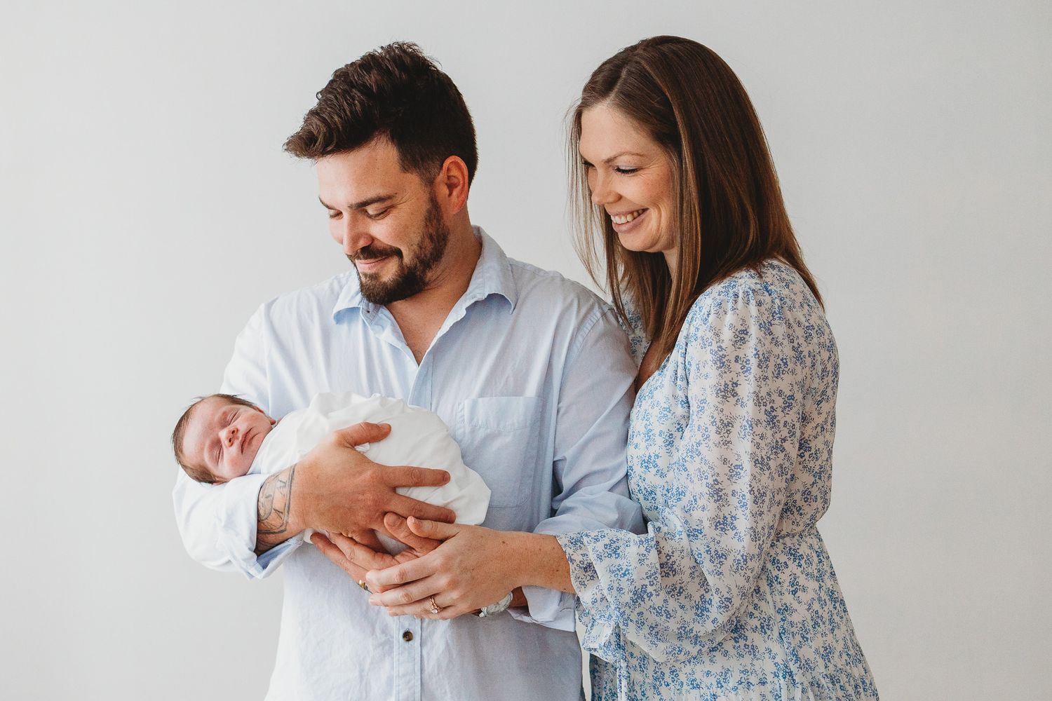 Natural light newborn photography session showing tender family moments in a bright room.