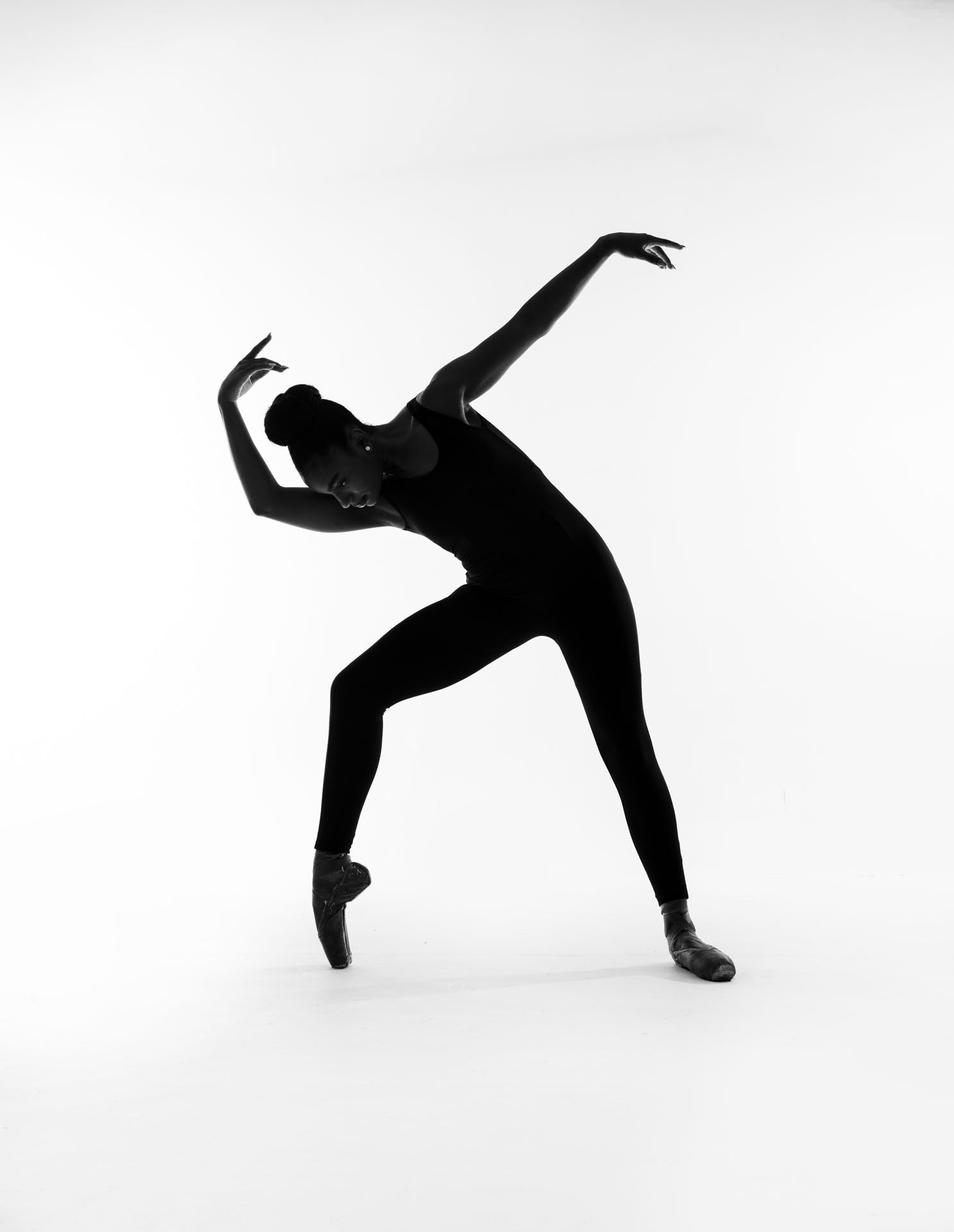 Silhouettes of dancers performing dynamic contemporary dance movements in black and white.