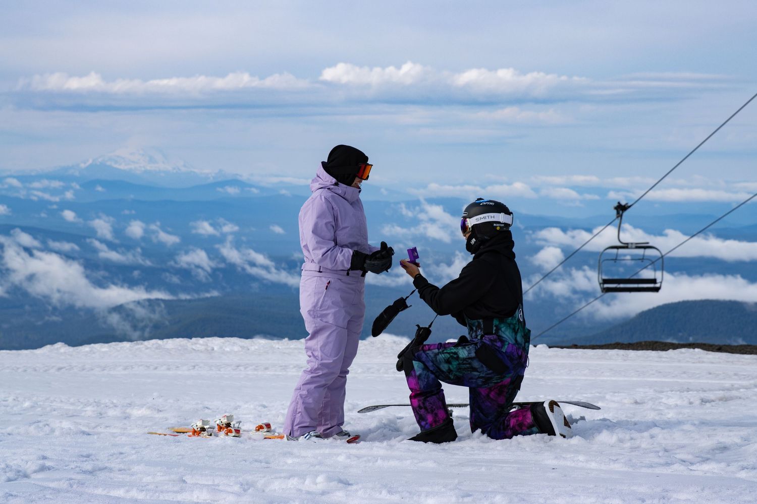 Man kneeling in the snow proposing to his partner at Timberline Lodge above the clouds. Mt. Hood Winter wedding Photographer.