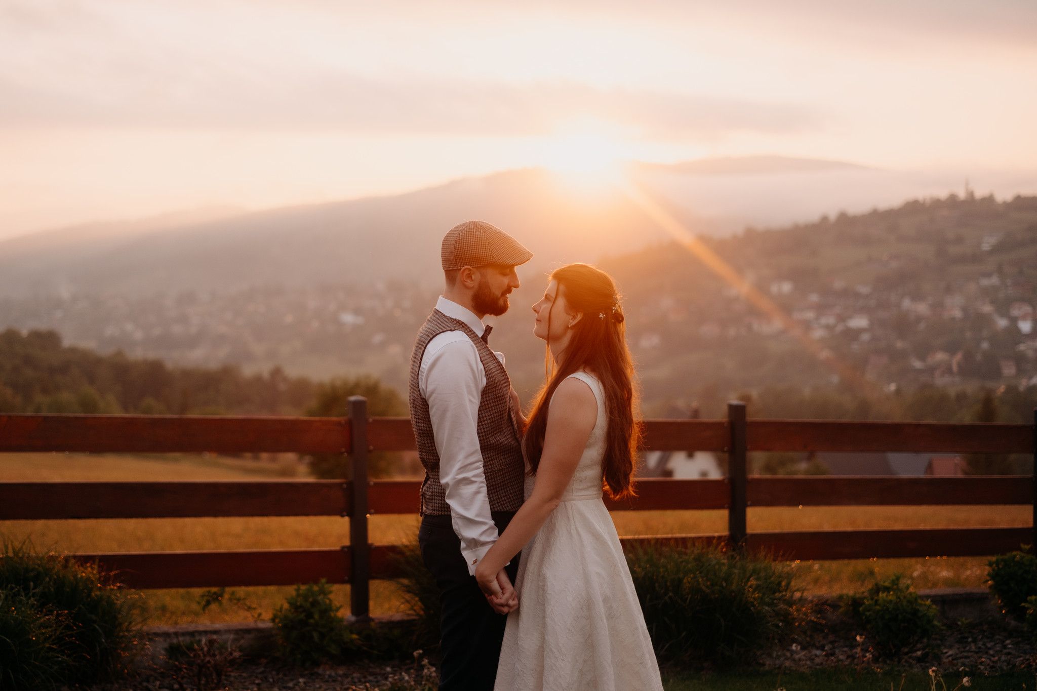 Couple shares intimate moment at sunset with mountain views.