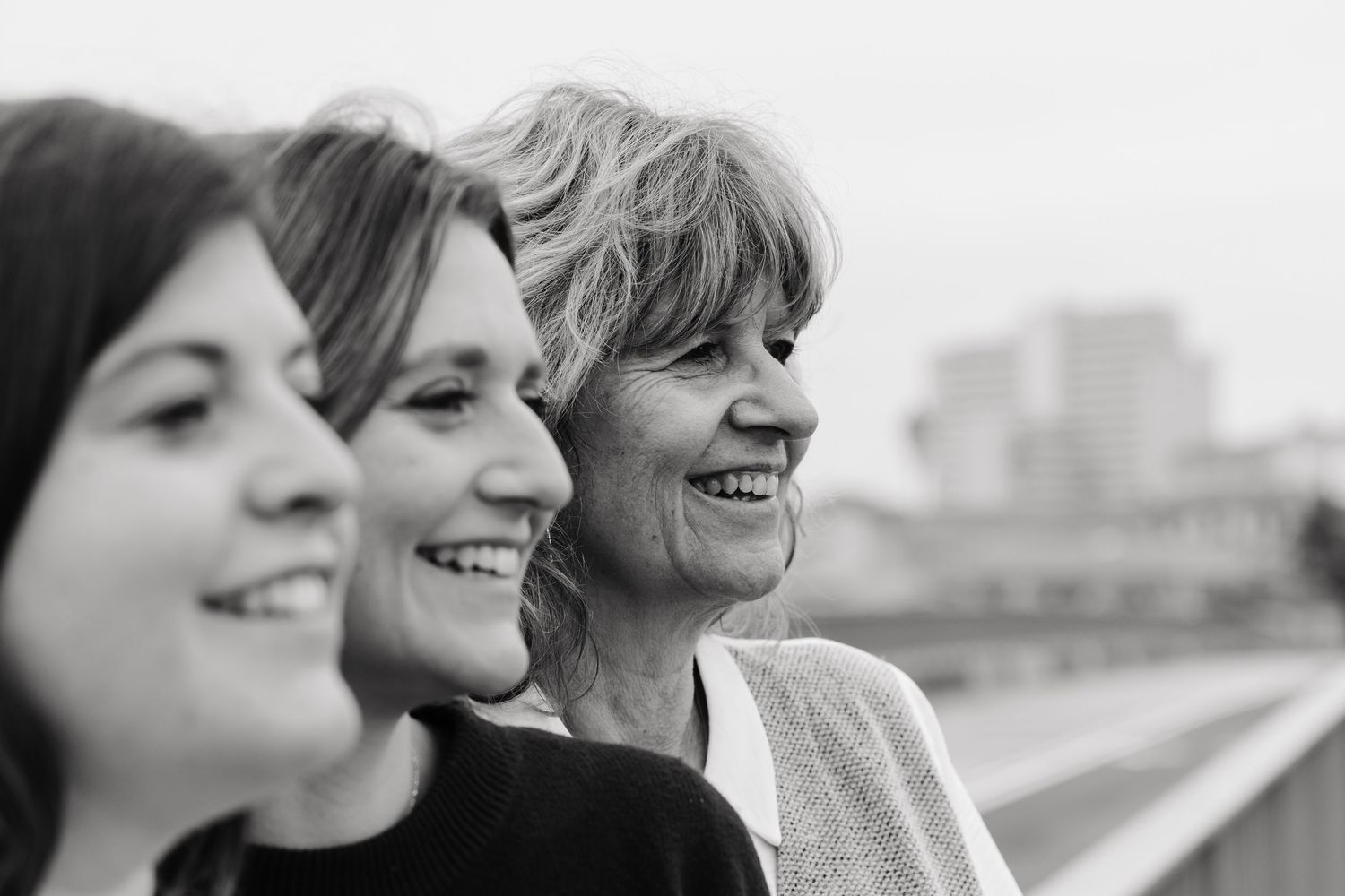 Three smiling women pose in a row in a black and white portrait taken in Toulouse, France.