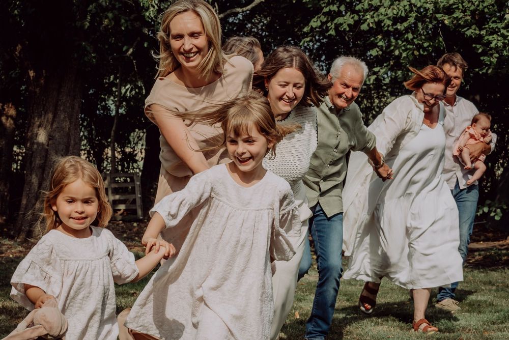 Happy multigenerational family laughing and running together through a beautiful green garden.