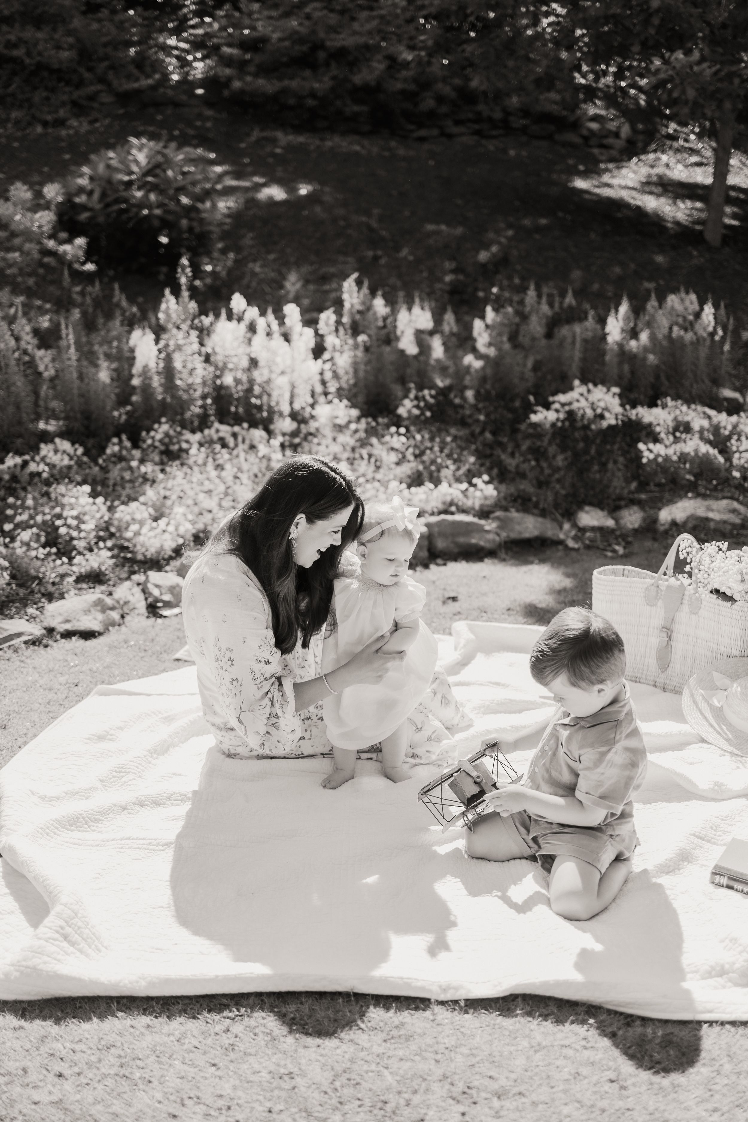 A sequence of black and white photos shows people sitting on a white blanket outdoors enjoying a picnic in nature.