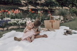 Romantic couple lying on a white blanket in a sunny outdoor setting during a picnic date.