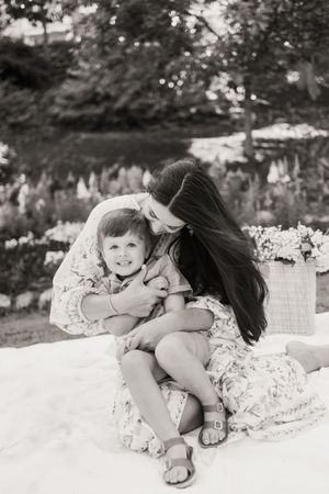 A series of black and white photos showing tender moments on a white blanket outdoors.
