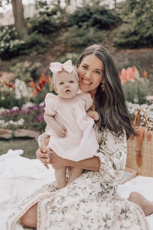 Sweet family portrait in garden setting with white picnic blanket and orange flowers.