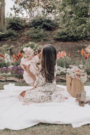 Relaxed outdoor family scene with wicker basket and floral garden backdrop.