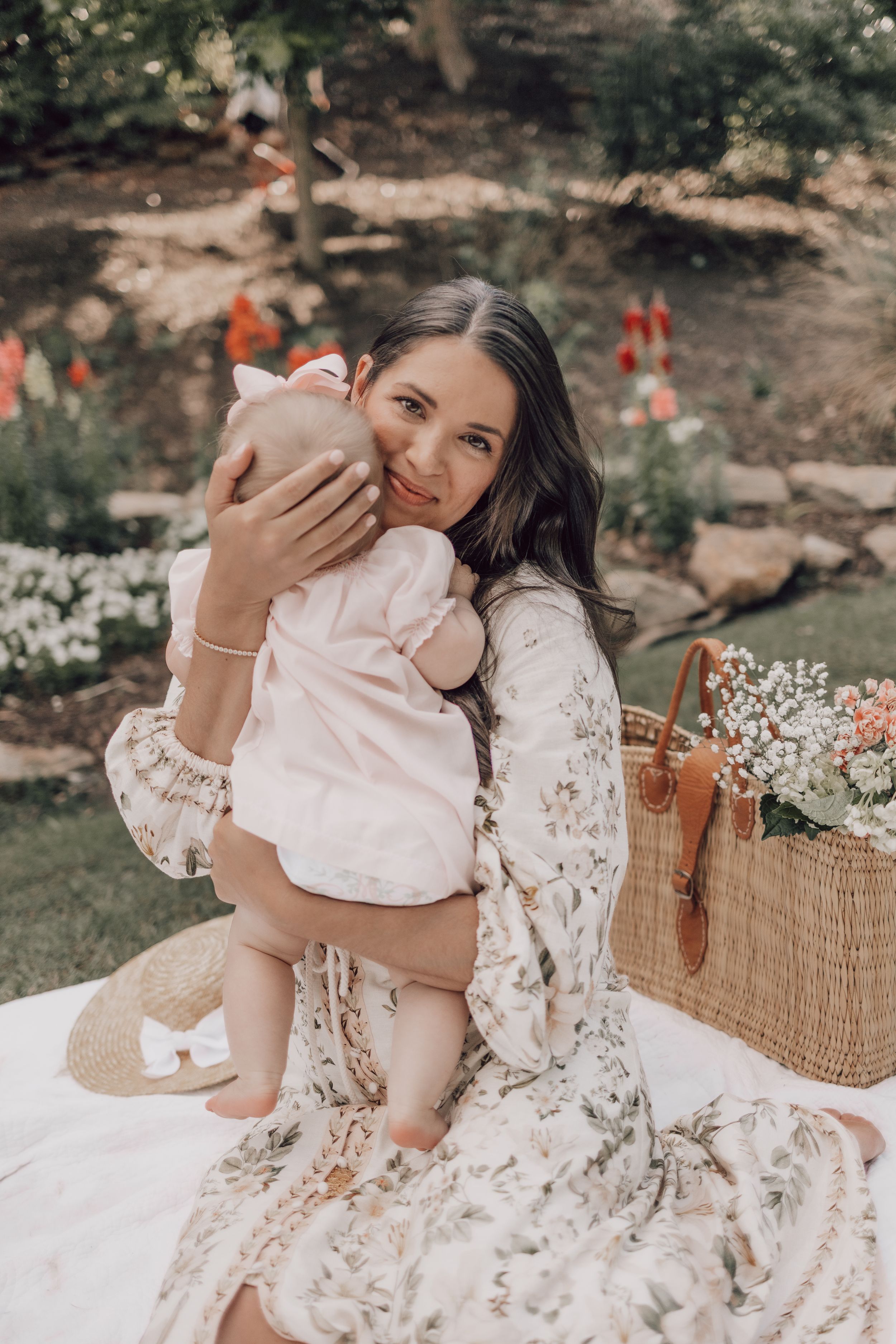An outdoor photoshoot featuring floral dress and white outfit against natural garden backdrop.