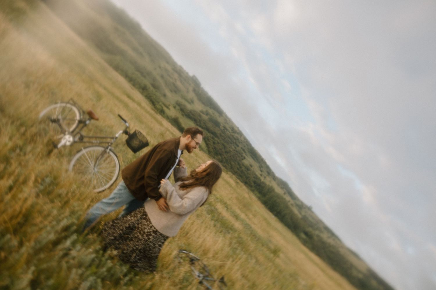 A romantic countryside scene with bicycles parked in golden grass under cloudy skies.