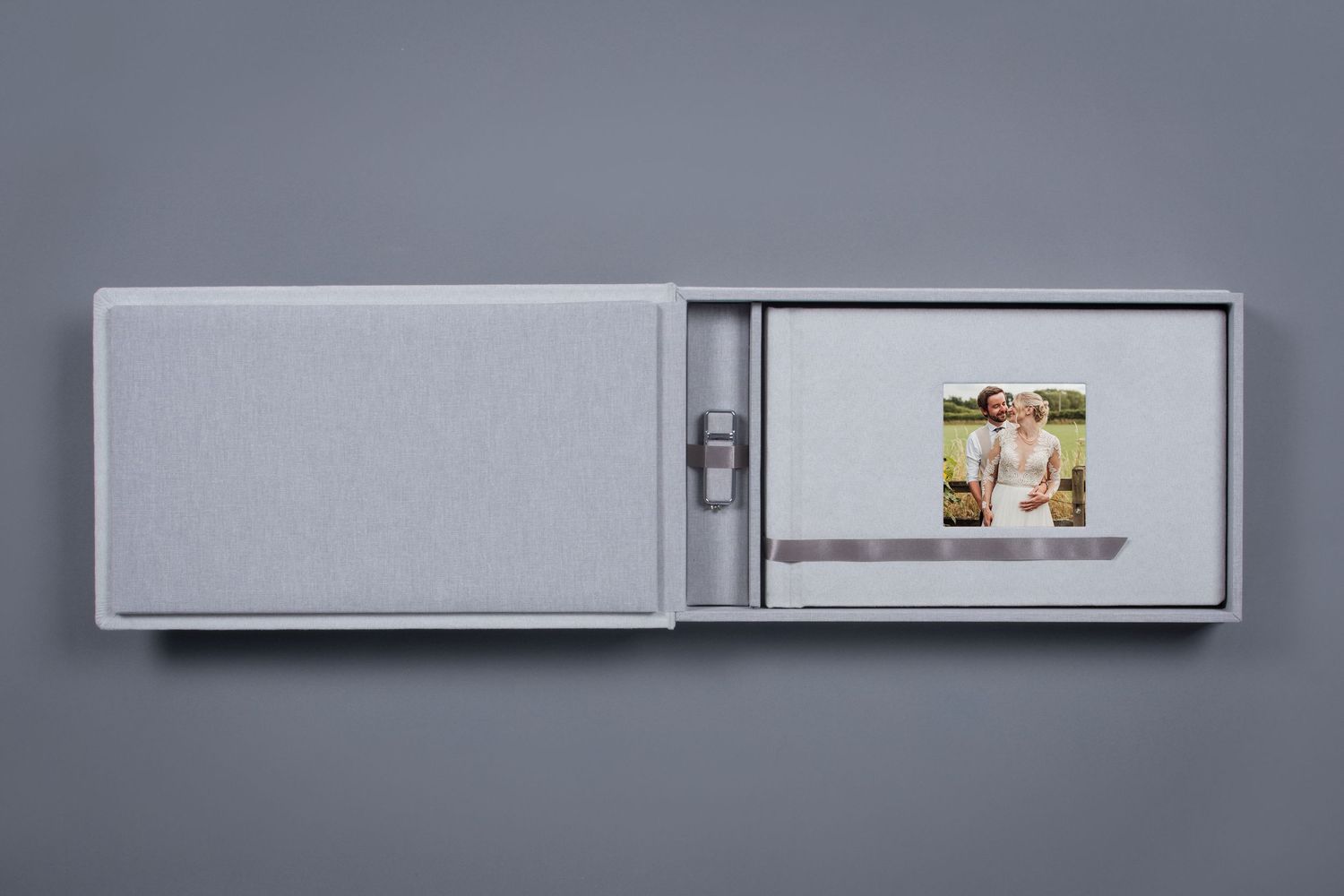 Elegant gray fabric photo box with USB drive and wedding photo print on gray background.