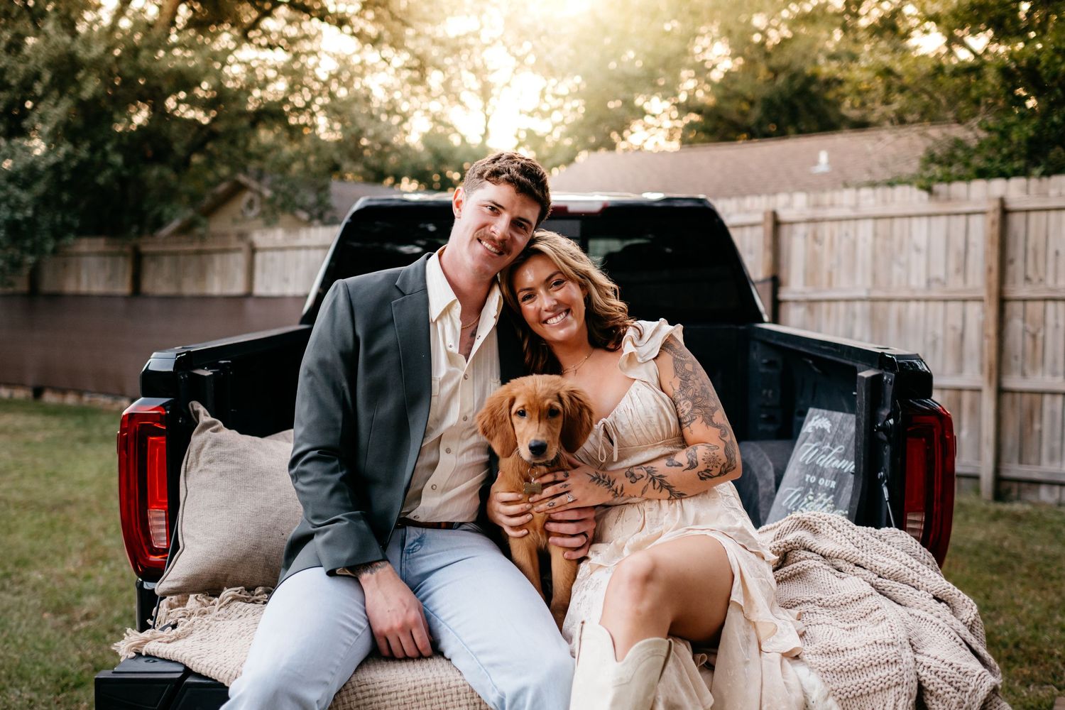 A cozy maternity photo session in the back of a pickup truck with a golden retriever dog at sunset. Pet friendly family portraits in Destin