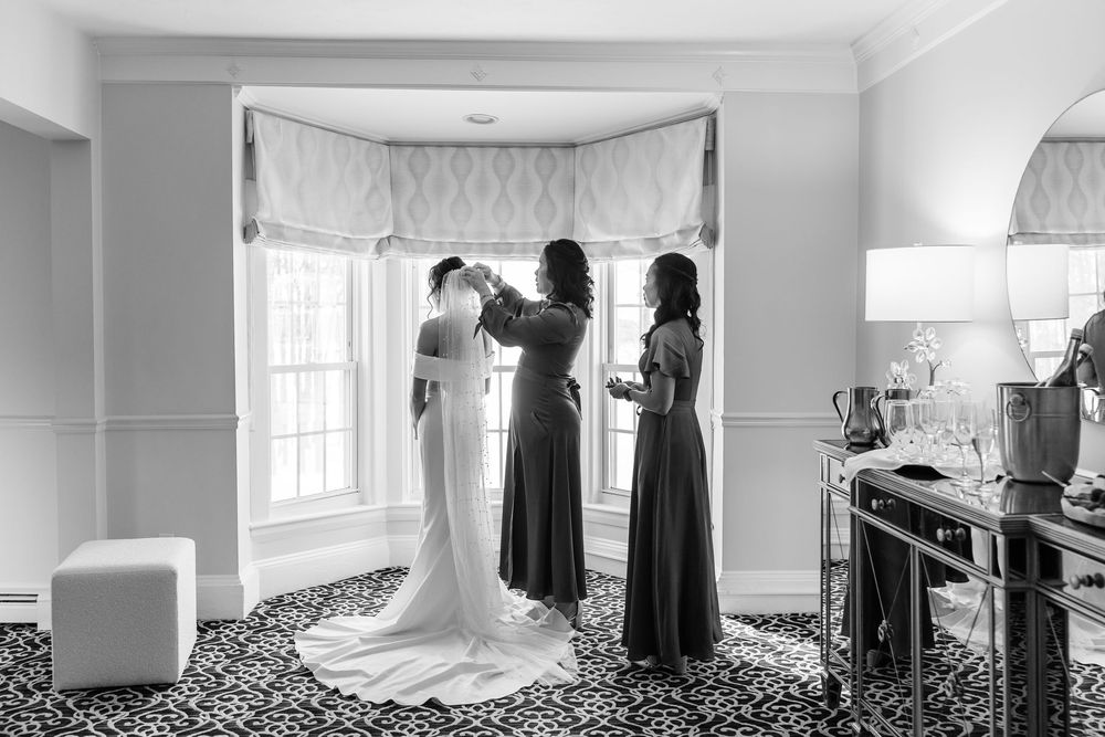Bridesmaids fastening bride’s wedding dress during getting ready moments at The Saphire Estate