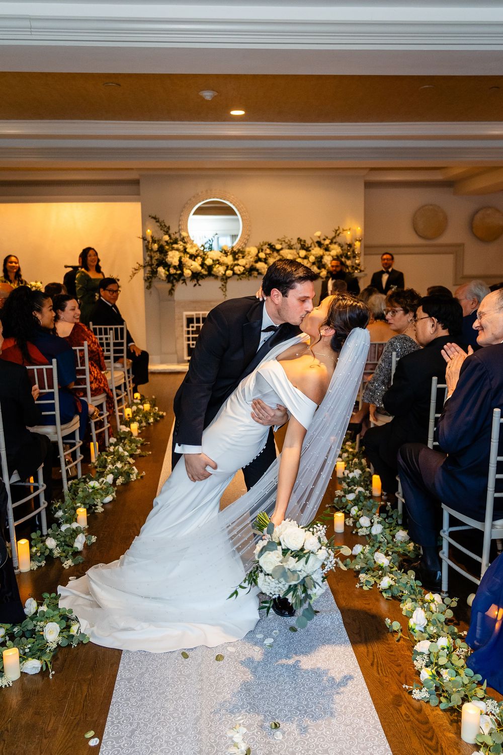Newlyweds share dip kiss during elegant indoor wedding ceremony at The Saphire Estate