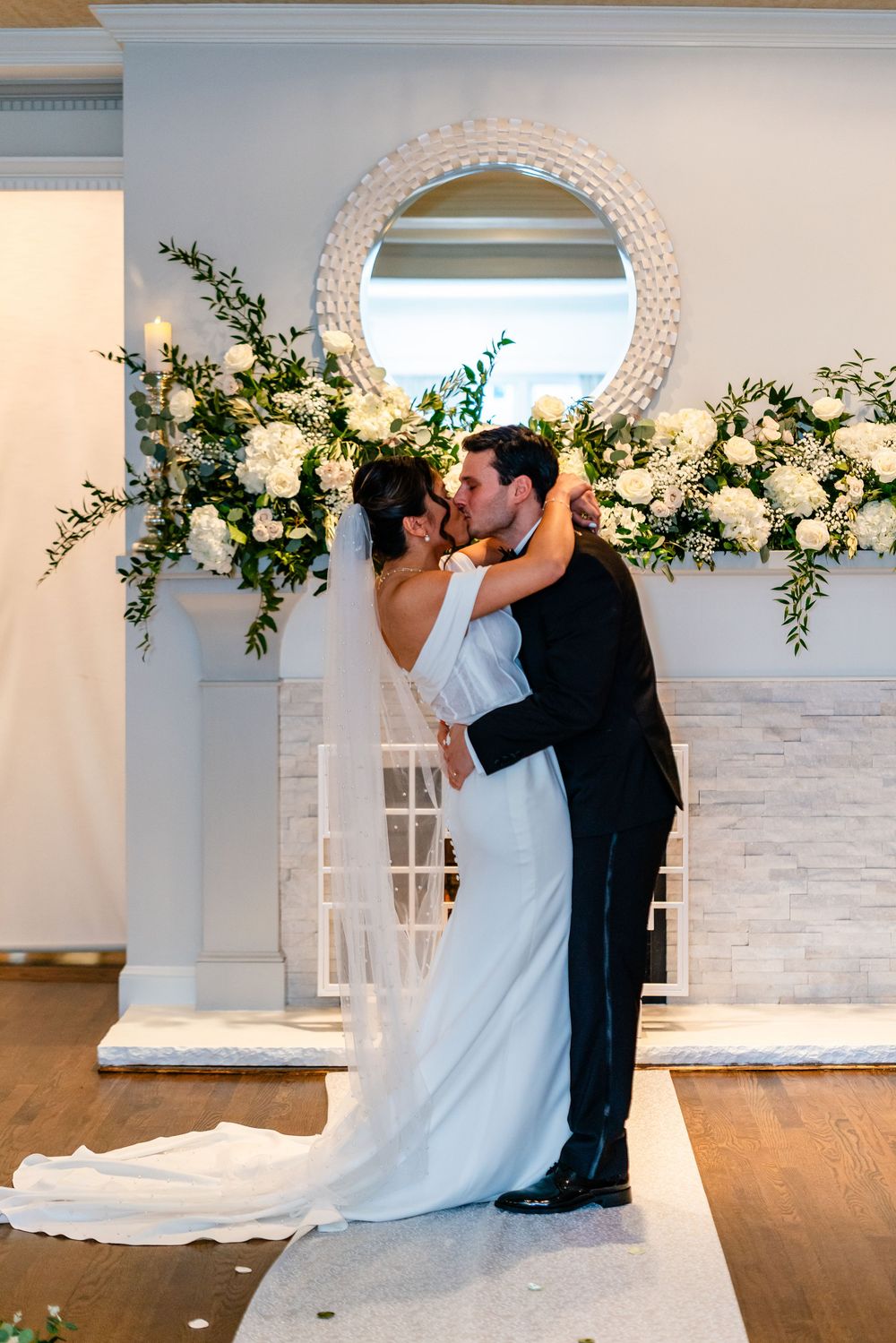 Romantic first kiss during indoor wedding ceremony at The Saphire Estate