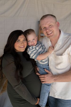 Happy family maternity portrait with pregnant mother, father, and young toddler son.