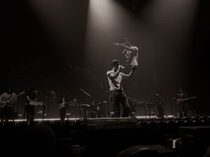 Band performing on a dramatic stage with spotlights and haze during a live concert.