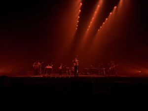 Band silhouetted on stage bathed in deep red atmospheric concert lighting.