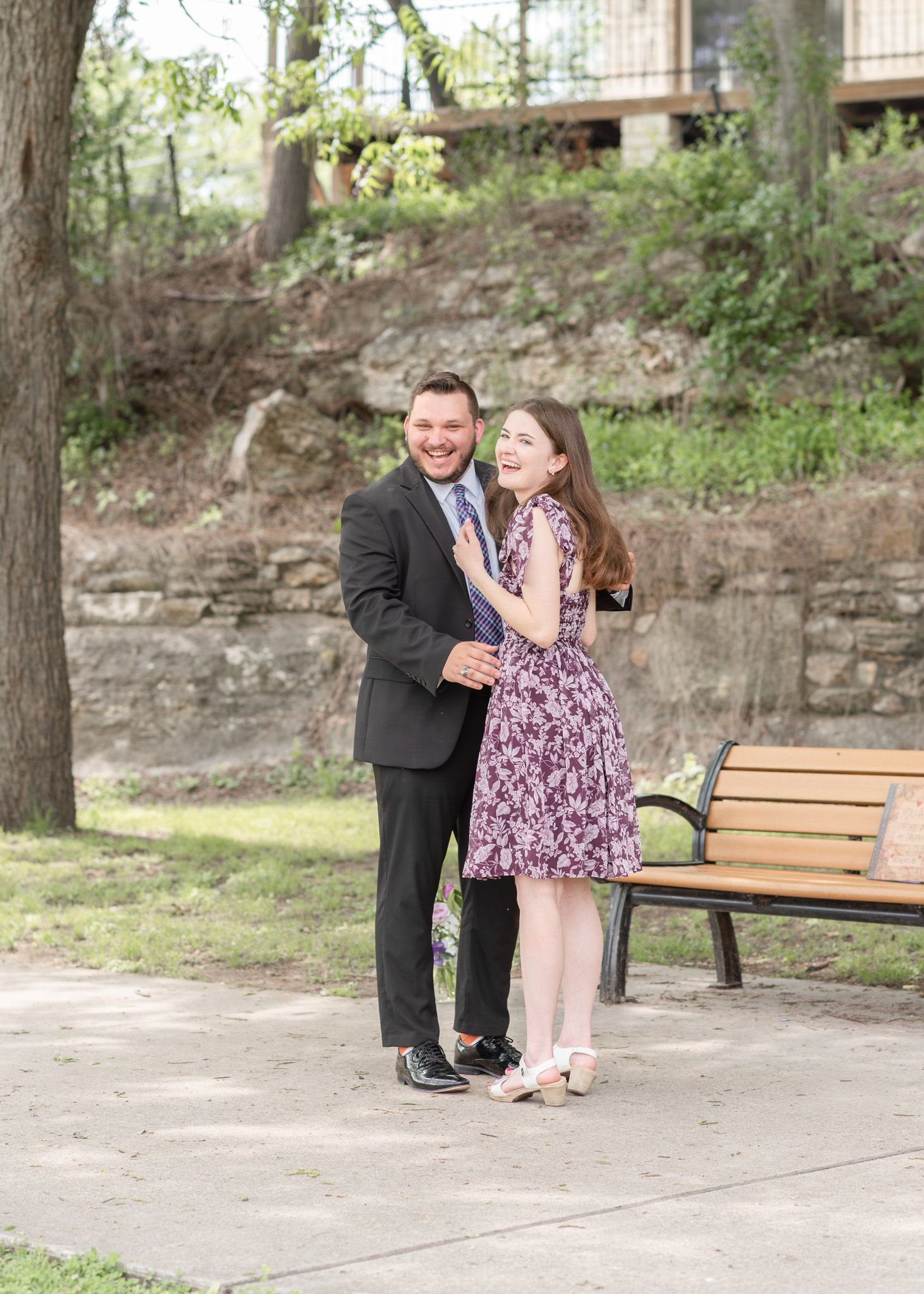 Engaged couple standing together near bench at Nolan Creek Trail in Temple Texas during outdoor engagement session