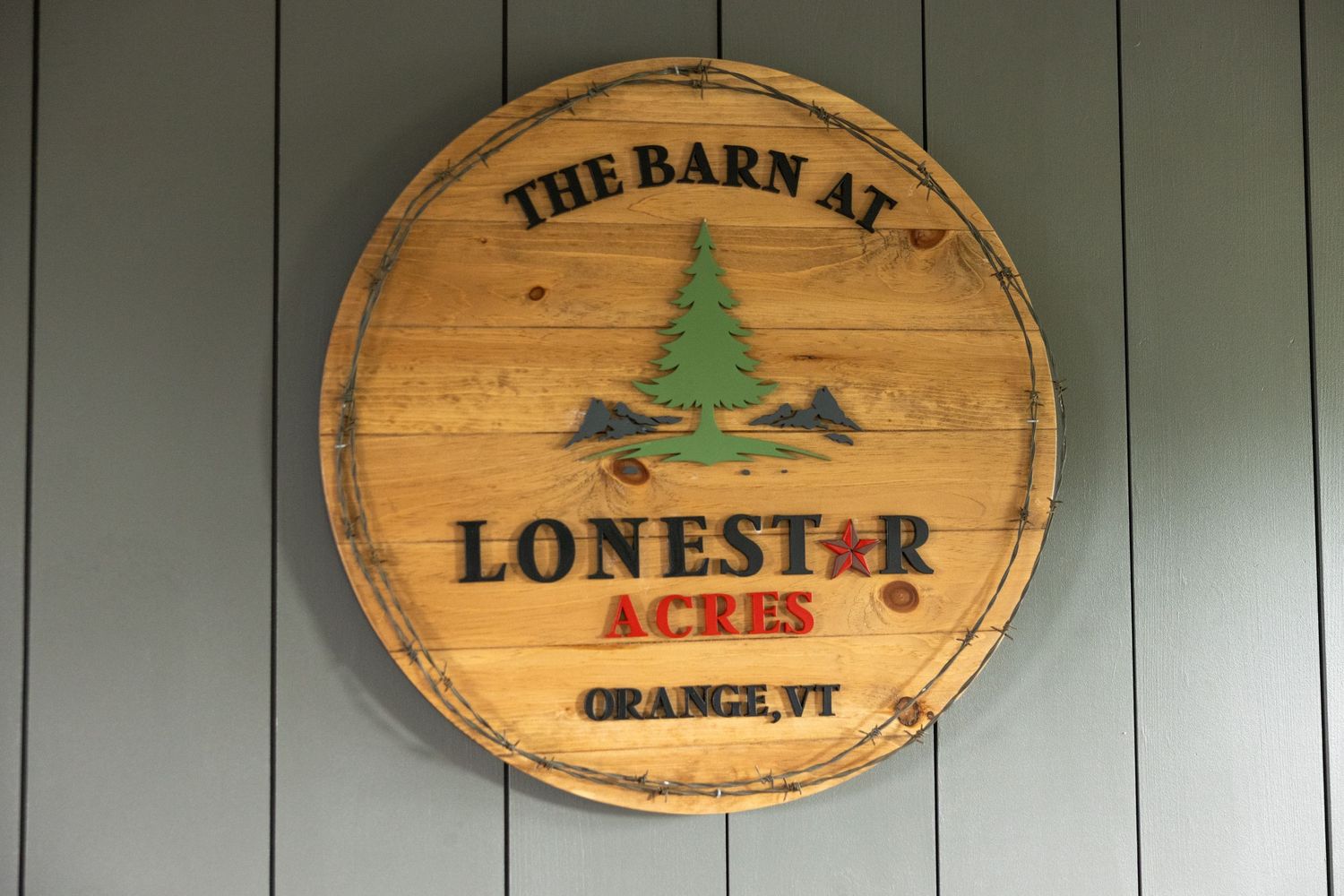 Rustic wooden barrel sign for The Barn at Lonestar Acres wedding venue in Orange, Vermont.