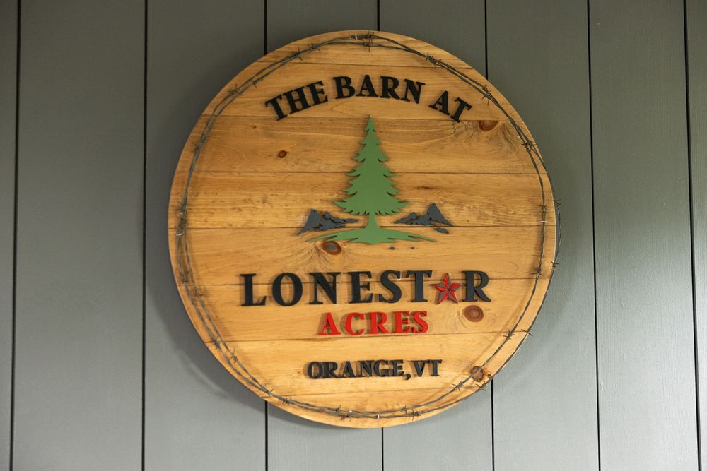 Rustic wooden barrel sign for The Barn at Lonestar Acres wedding venue in Orange, Vermont.