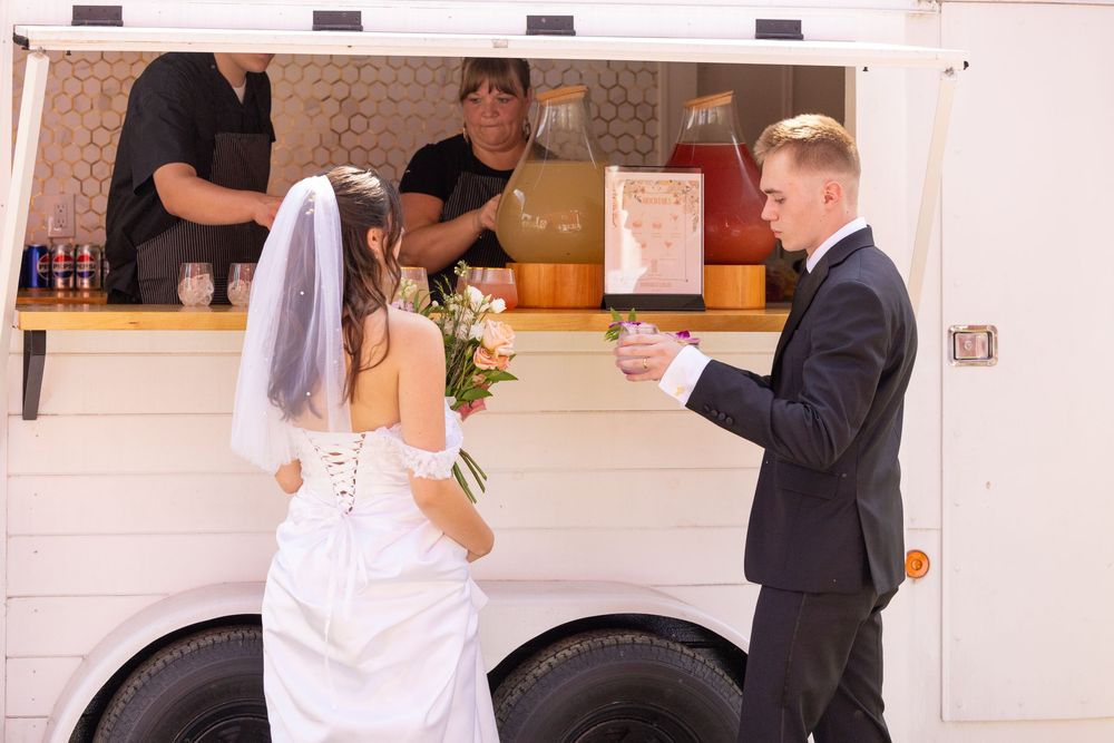 Bride and groom ordering from a white food truck at their wedding reception.
