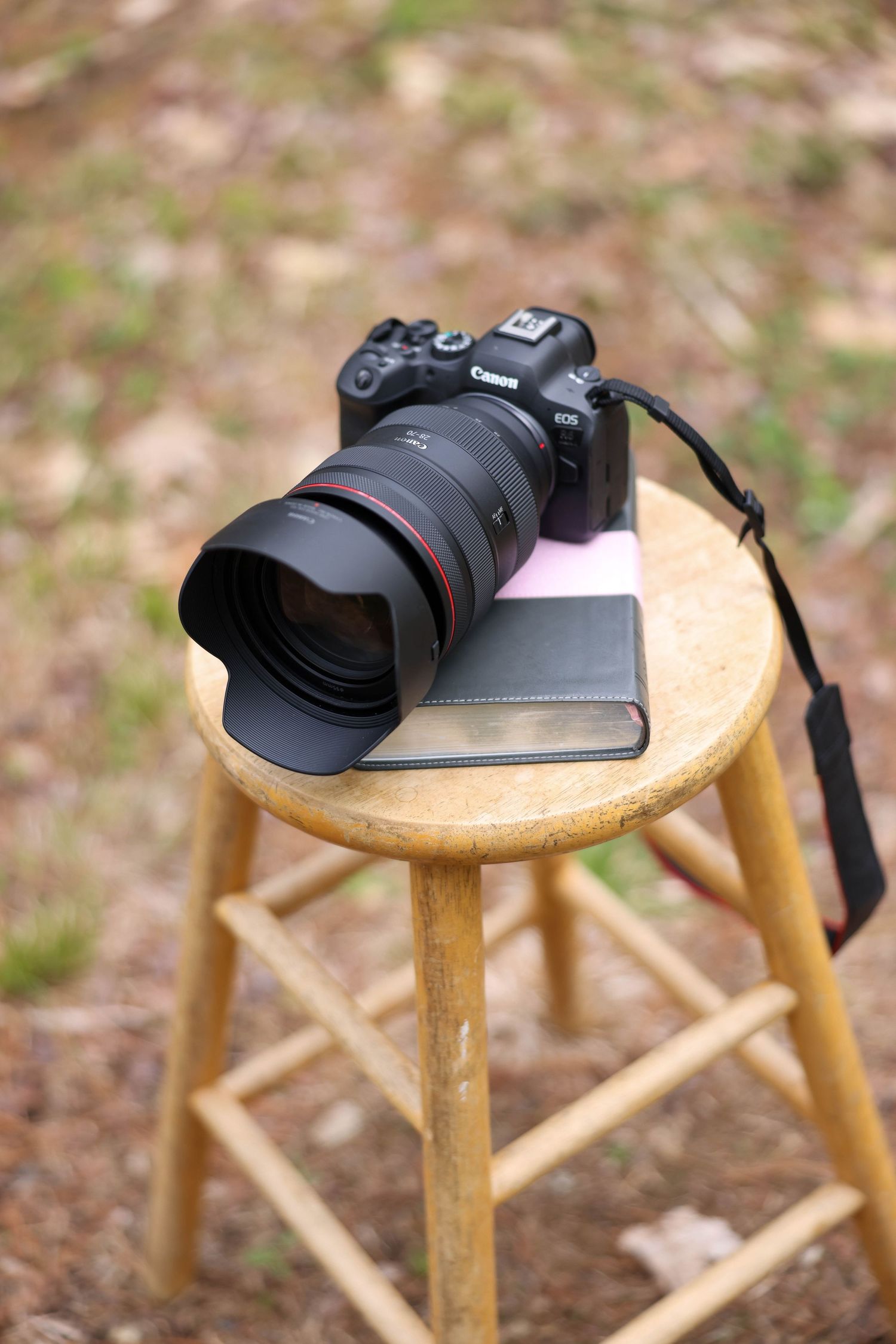 Canon EOS camera with zoom lens resting on a wooden stool outdoors during a wedding shoot.