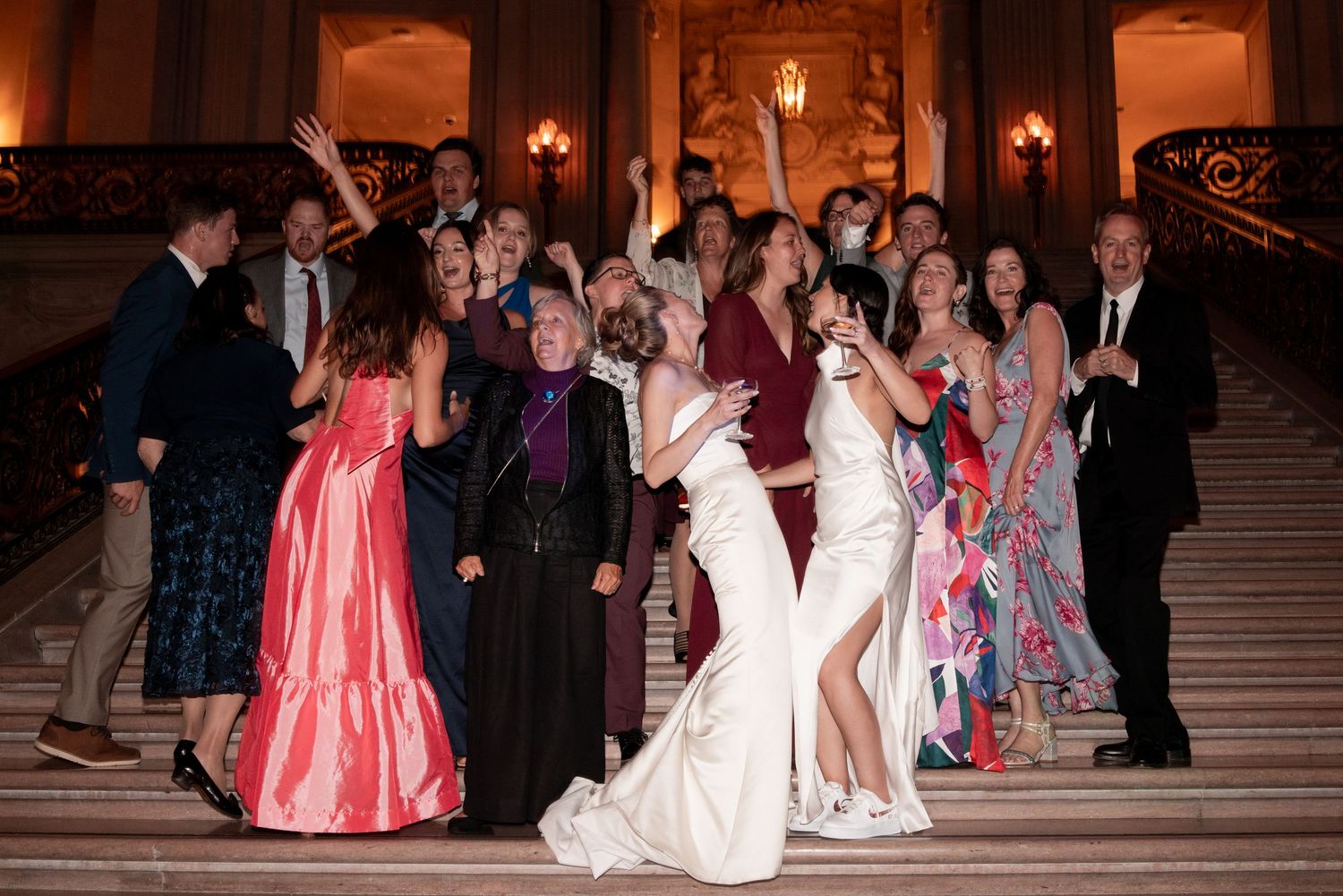 Bride lifted by guests during lively wedding reception dance celebration with warm amber lighting.