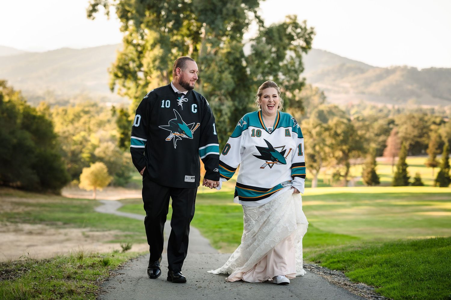 Bride and groom pose in front of cactus garden with golden mountain backdrop at outdoor wedding.