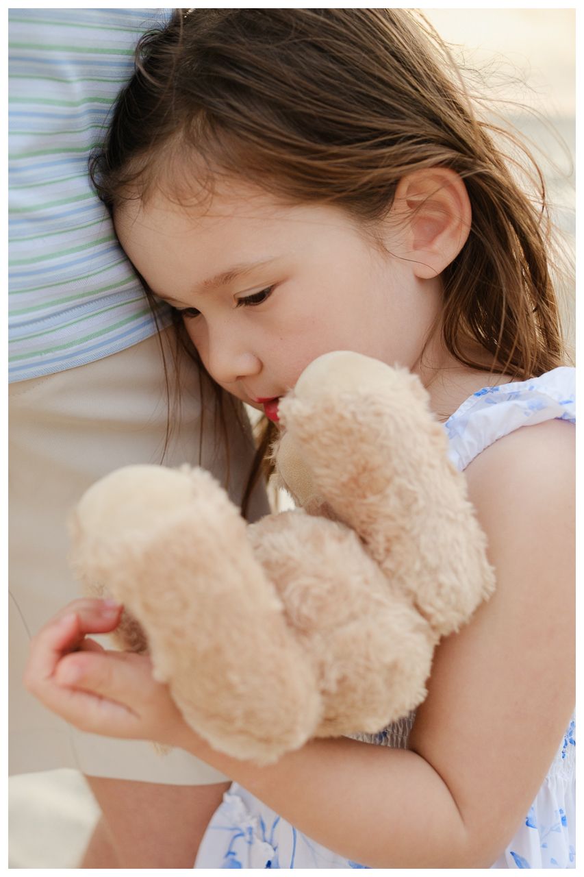 Family vacation photography at Villa del Palmar Flamingos of a young girl hugging her teddy bear.