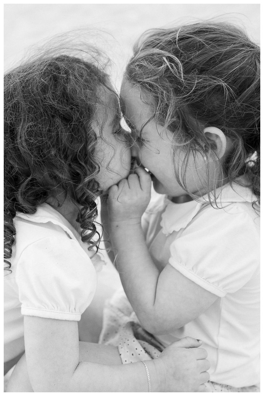 Family photography at Villa del Palmar Flamingos of two sisters laughing together in a black and white portrait.