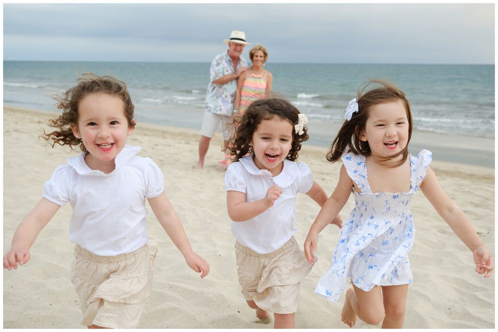 Beach family photos at Villa del Palmar Flamingos of three girls running on the sand with grandparents behind them.