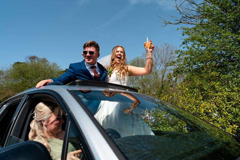 Bride and Groom standing up in car on their Wedding day at Nancarrow Farm