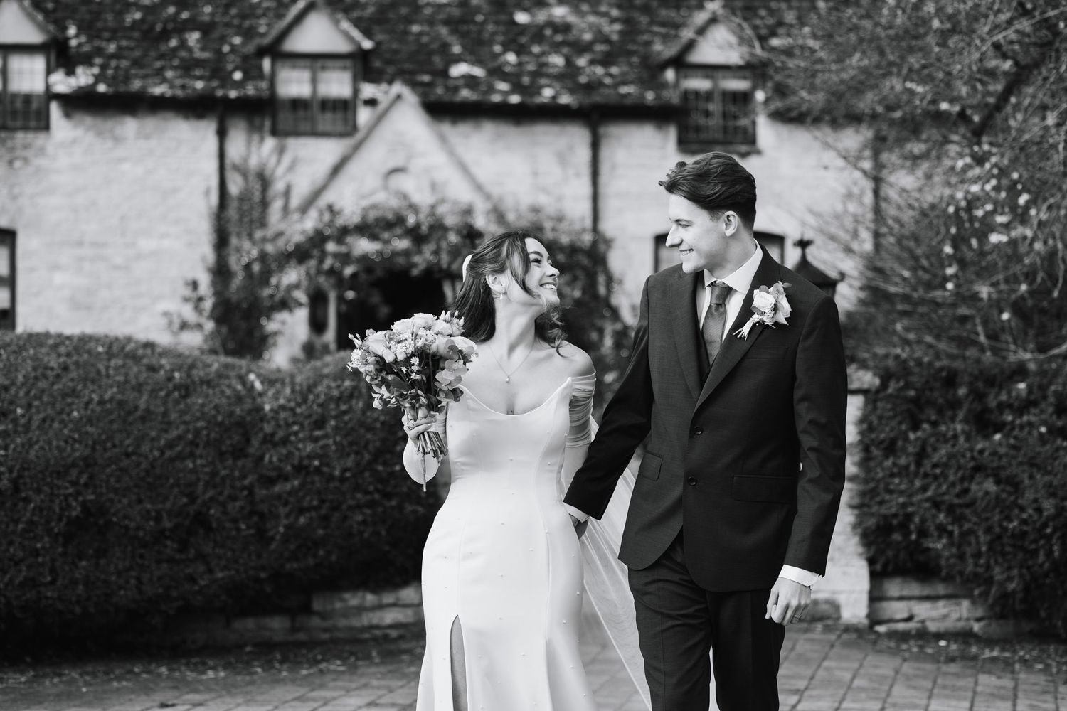 Black and white photo of a bride and groom walking together outside Minster Mill wedding venue
