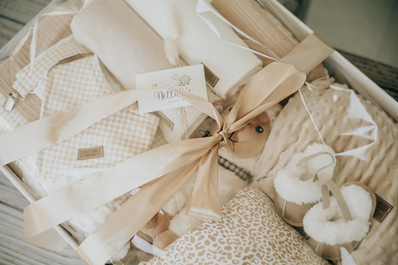 Baby nursery set with giraffe print blankets, burp cloths, and muslin wraps displayed in a wicker basket.