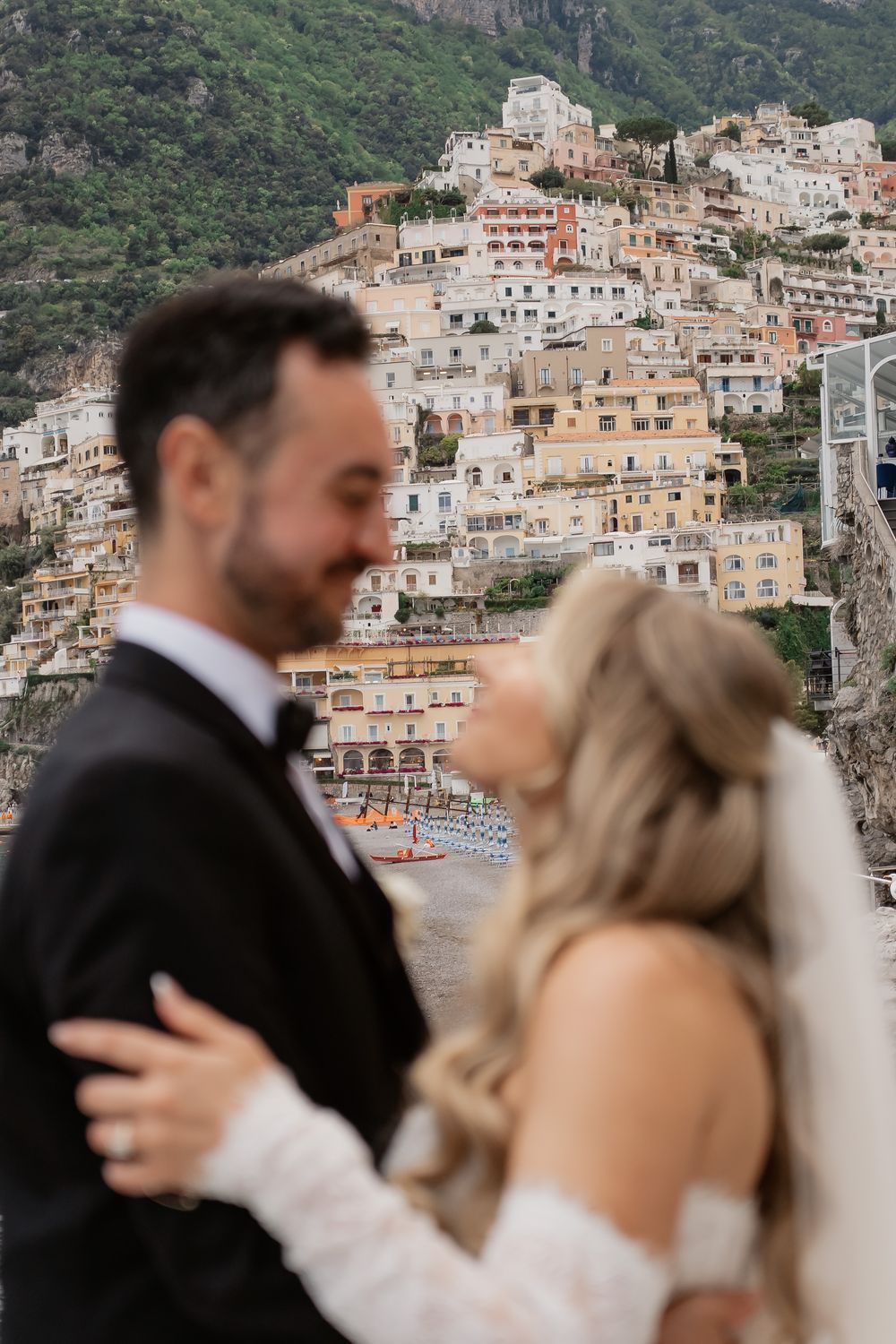 Bride and groom embrace with stunning Positano cliffside village backdrop on the Amalfi Coast during their wedding day.