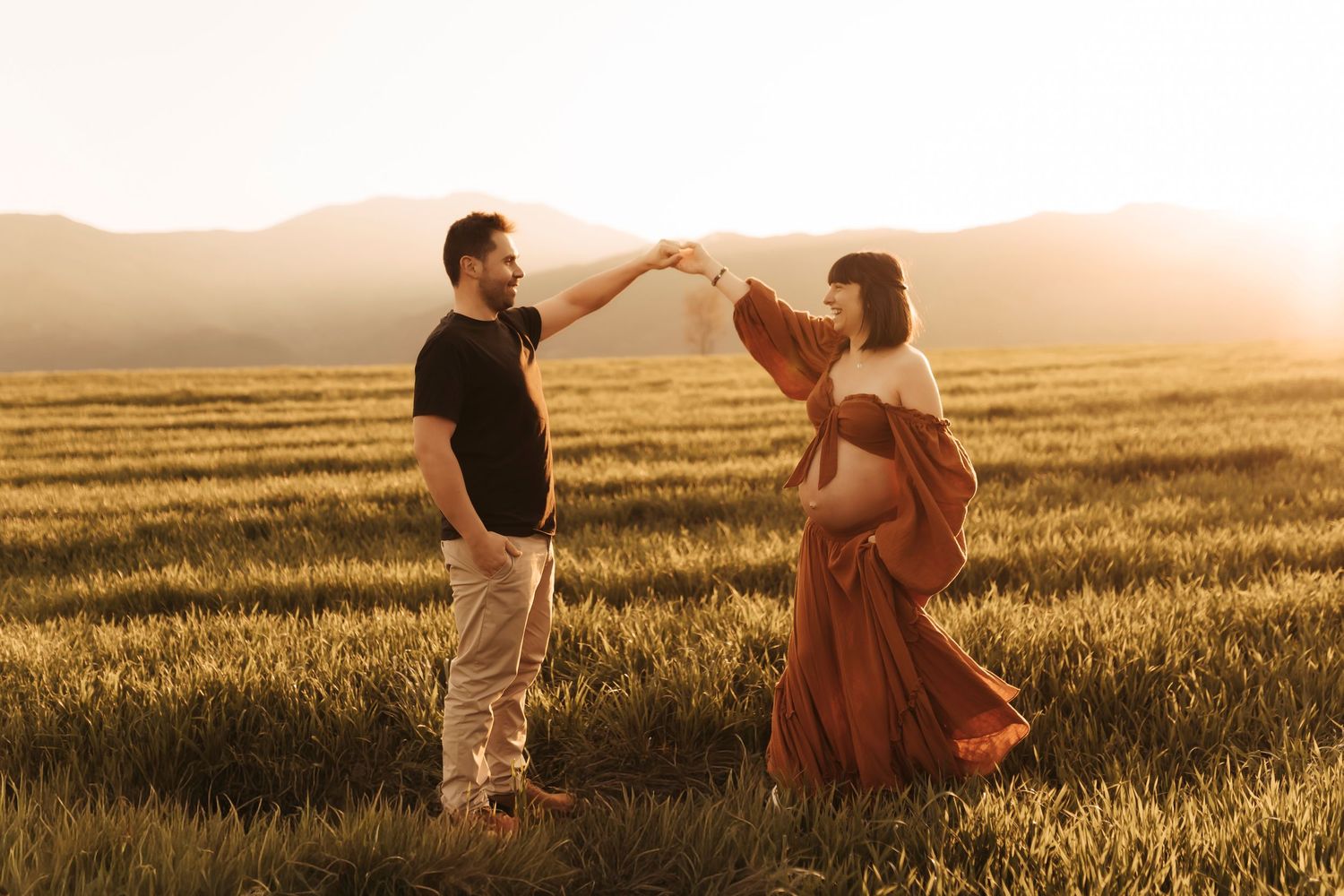 Pareja esperando un bebé durante una sesión de fotografía de embarazo en la naturaleza.