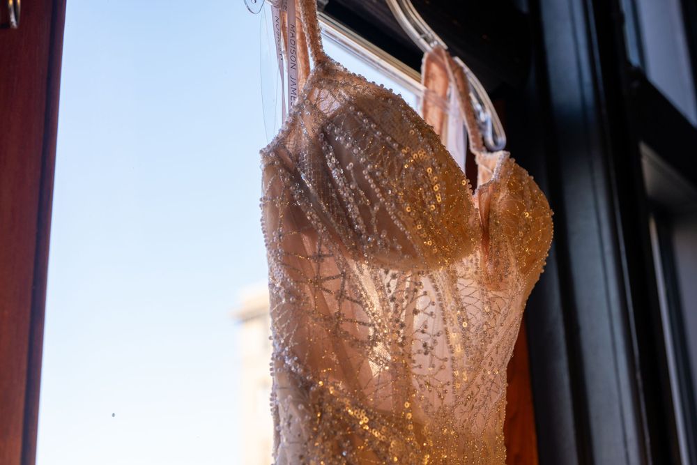 A roasted duck hangs in a restaurant window display with glistening brown glazed skin.