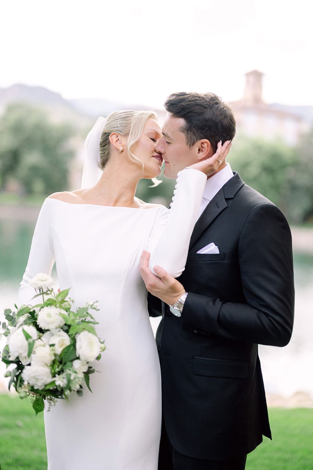 A romantic wedding photo showcasing a classic white bridal gown and black tuxedo.