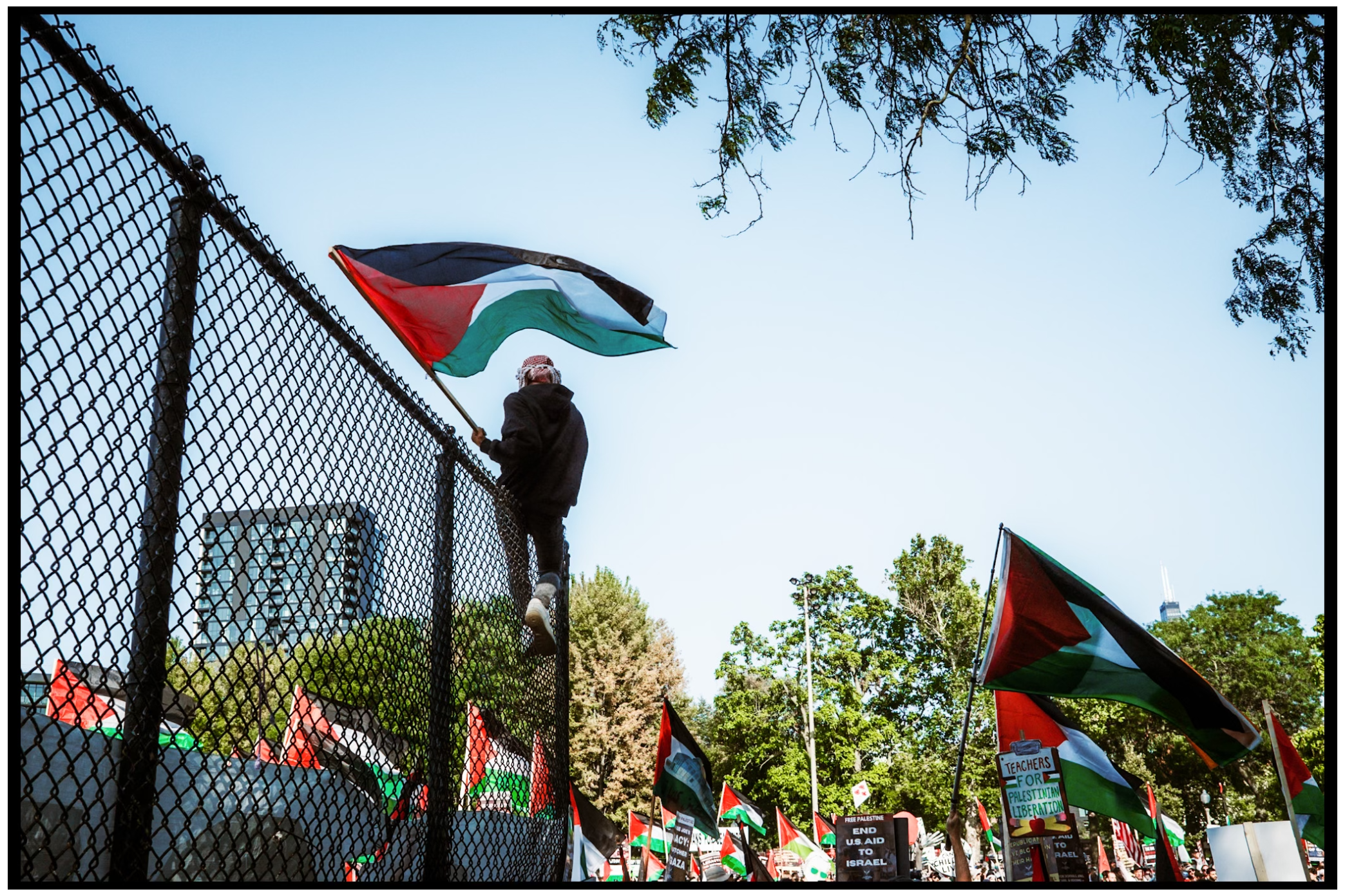 Palestinian flags wave atop a chain link fence during a protest demonstration. Chicago. March on DNC