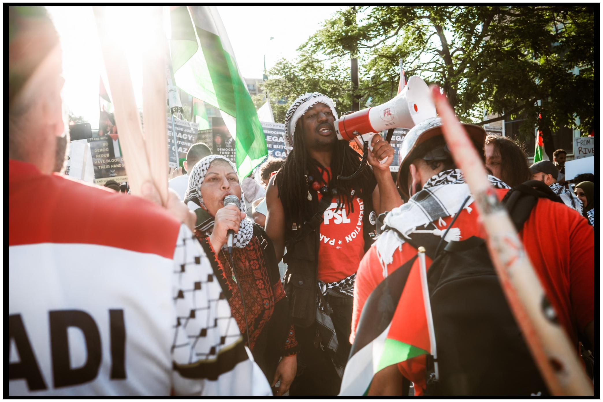 Crowd of protesters wave Palestinian flags and demonstrate outdoors in bright sunlight. Chicago. March on DNC
