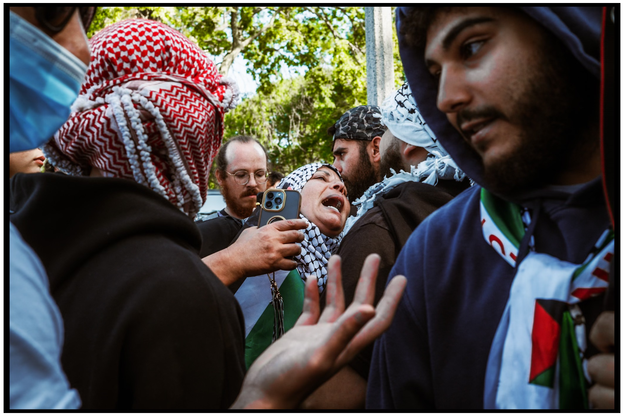 Protesters wearing traditional keffiyehs gather in close conversation during a demonstration. Chicago. March on DNC