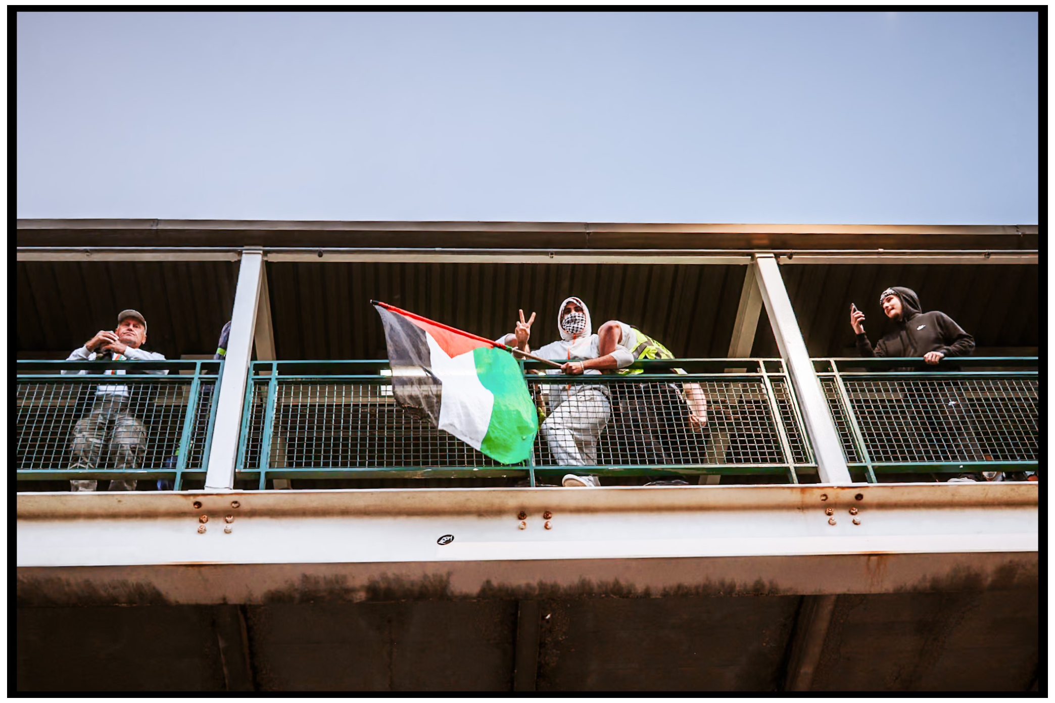 Demonstrators wave Palestinian flags from a balcony railing during a protest event. Chicago. March on DNC