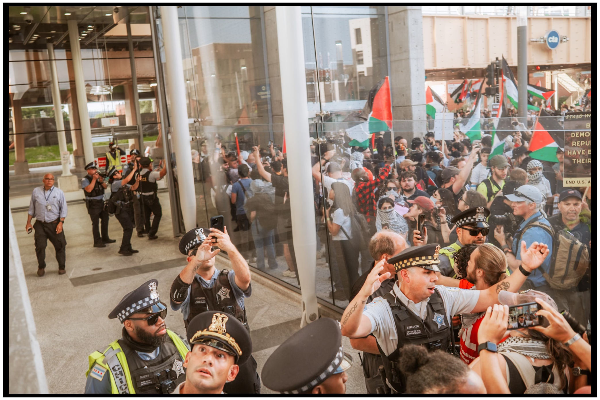 Protesters and police officers gather around pillars while people take photos. Chicago. March on DNC