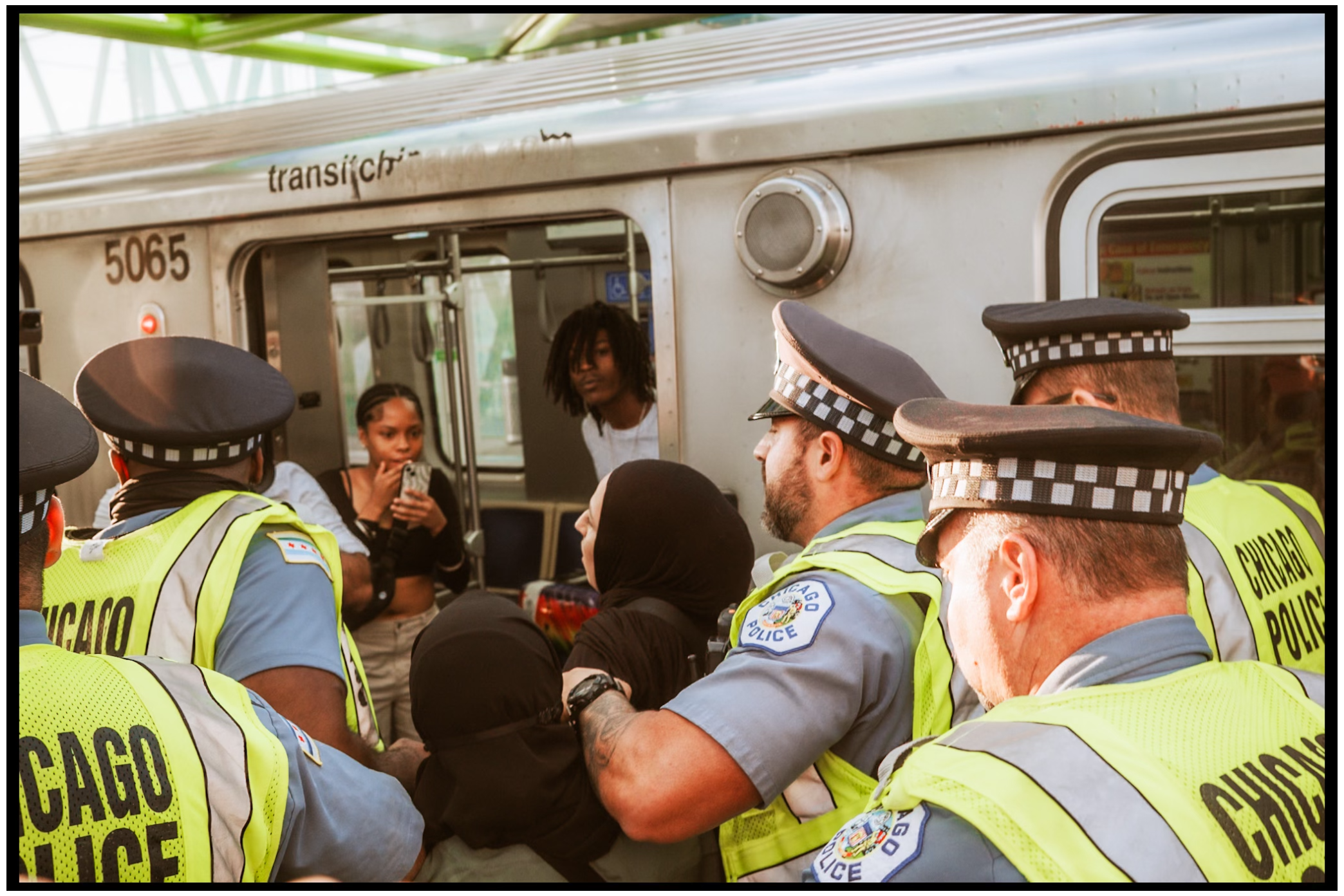 Police officers in high-visibility vests interact with people at transit station. Chicago. March on DNC