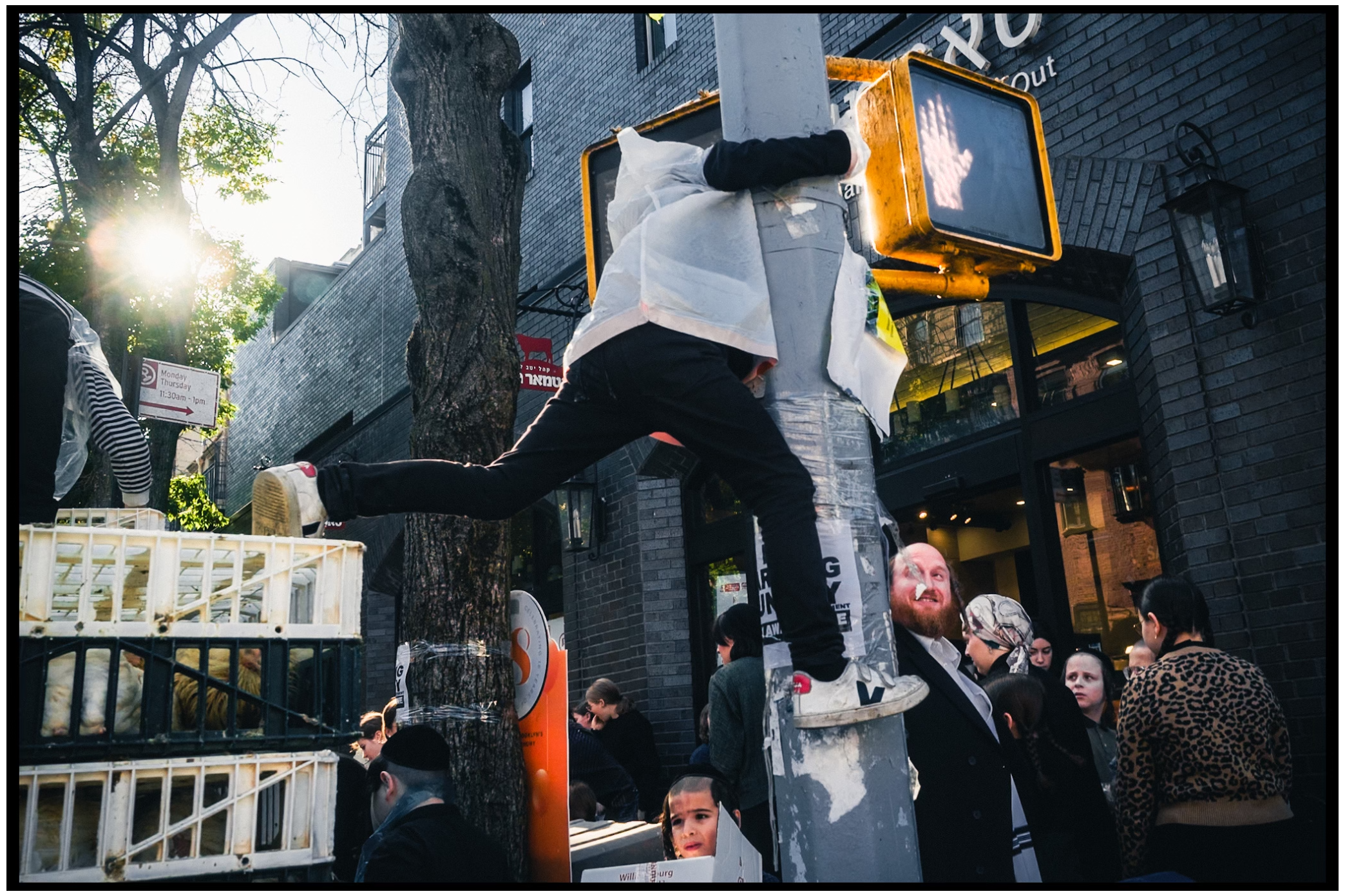 Dynamic street photography showing people climbing and jumping near a building entrance. Kapparot, Brooklyn NYC