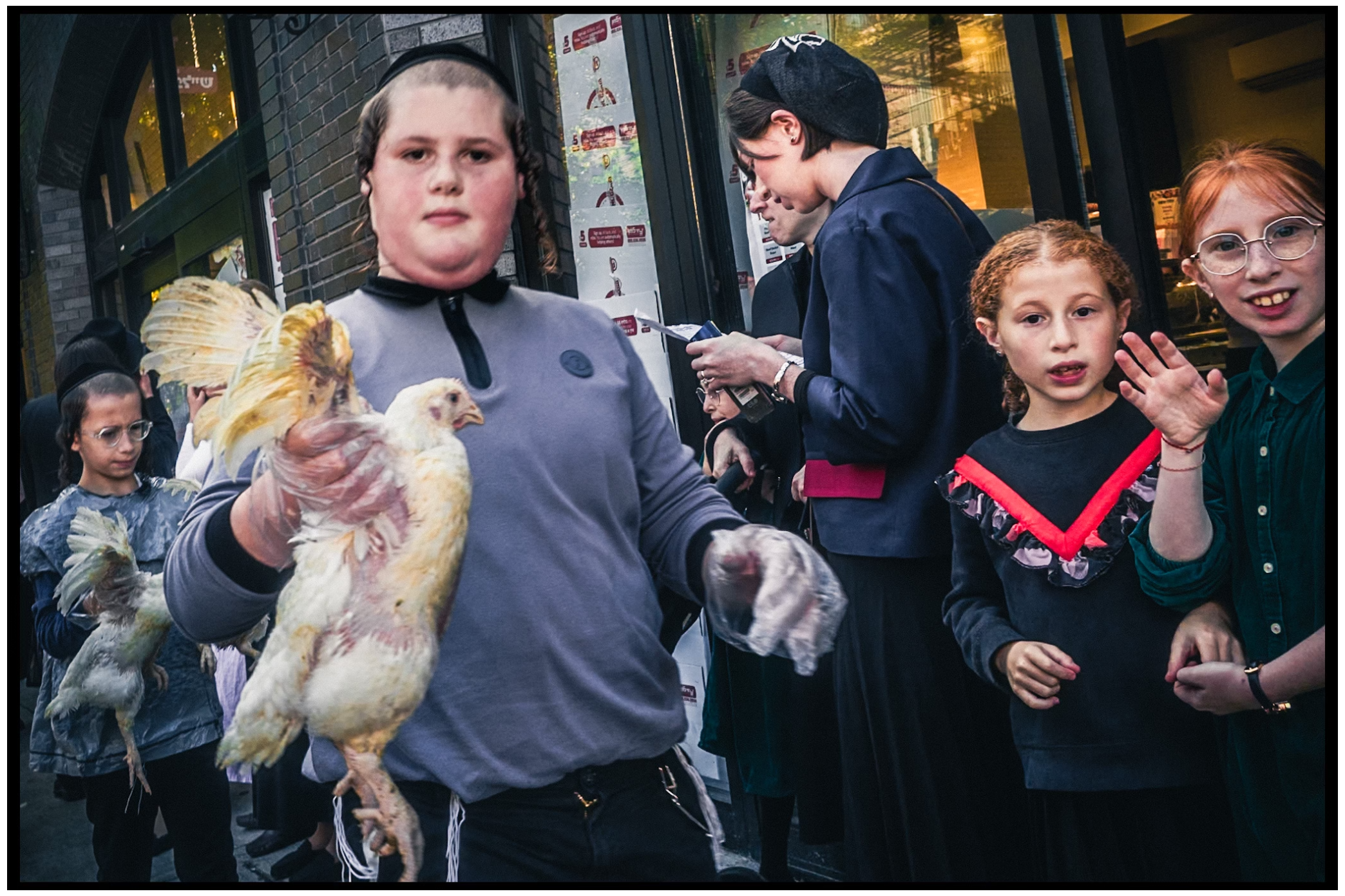 People participate in a traditional Kapparot ceremony holding white chickens on a busy street. Kapparot, Brooklyn NYC